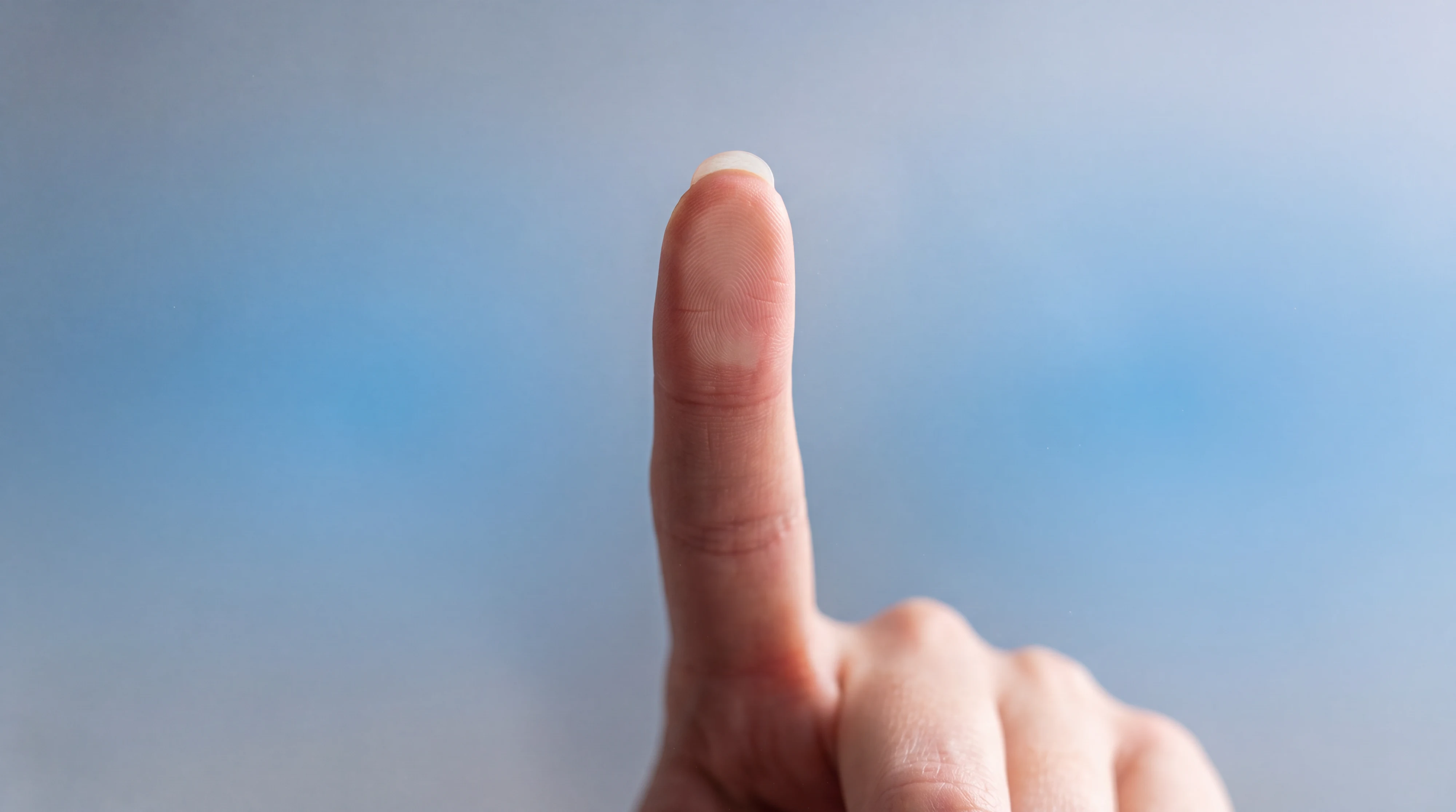 A fingertip presses a pane of fogged glass. A button lights where it touches and the fog clears.